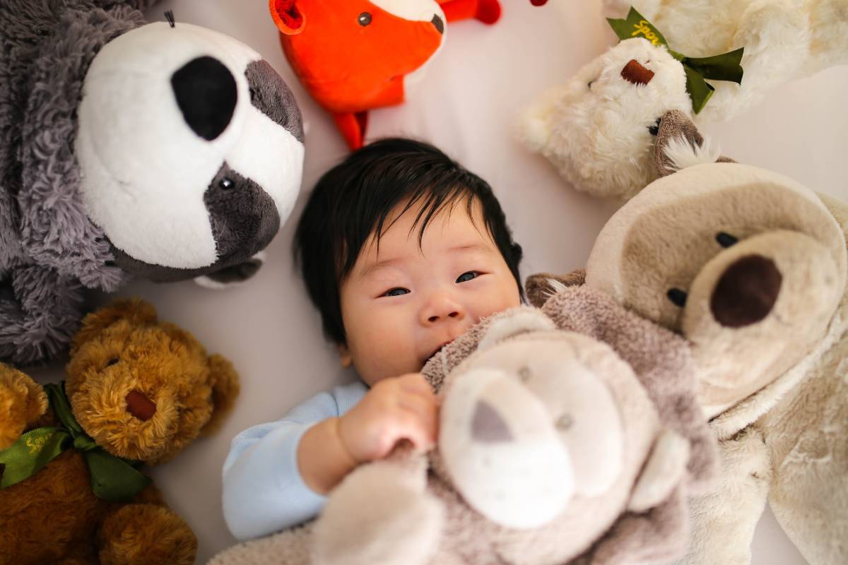 bébé entouré de peluches et doudous