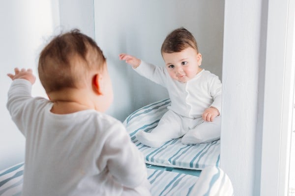 Un bébé assis devant le miroir 